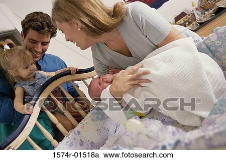 Stock Image - Mother placing her baby into a crib. Fotosearch