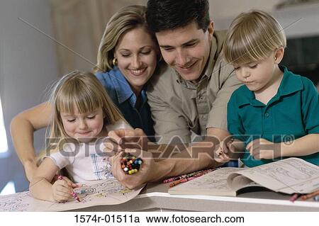 Stock Image - Parents and their children drawing in a coloring book. Fotosearch