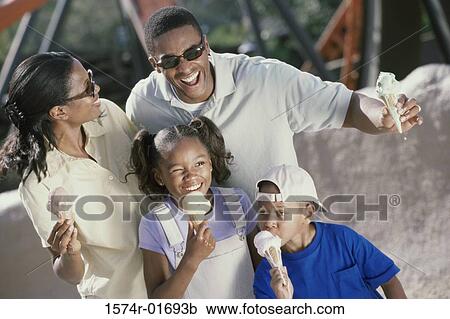 Stock Image - Parents and their two children eating ice cream cones. Fotosearch
