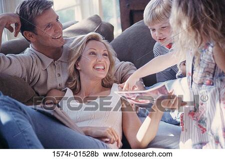 Stock Image - Parents and their two children together on a bed. Fotosearch
