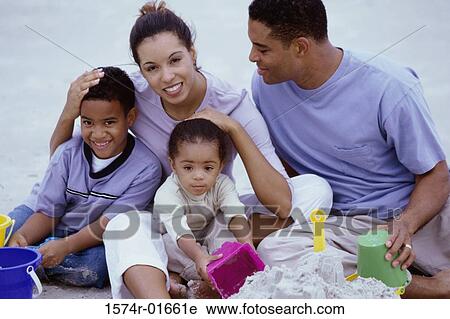 Stock Image - Portrait a young couple together at the beach with their children. Fotosearch
