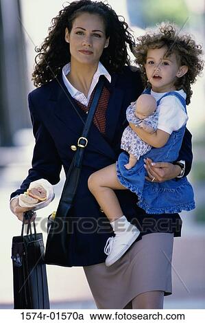Stock Image - Portrait of a businesswoman carrying her daughter. Fotosearch