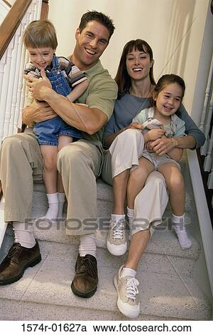 Stock Image - Portrait of a couple sitting on steps with their son and daughter. Fotosearch