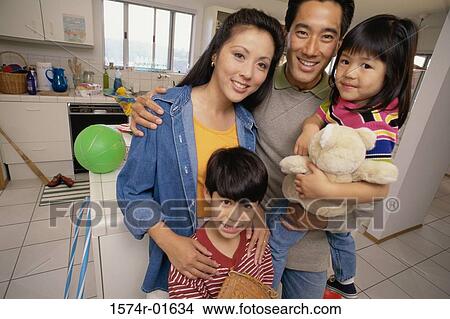 Picture - Portrait of a couple standing in the kitchen with their son and daughter. Fotosearch