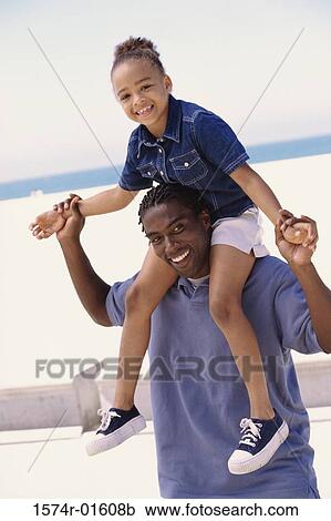 Stock Image - Portrait of a man carrying his daughter on his shoulders. Fotosearch