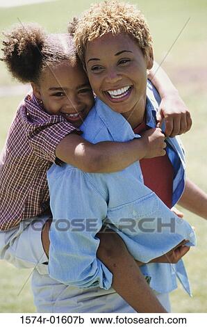 Stock Image - Portrait of a woman carrying her daughter on her back. Fotosearch