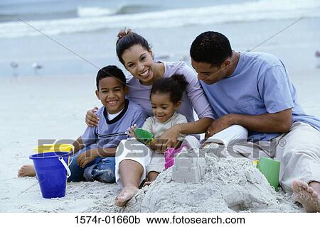 Stock Image - Portrait of a young couple and their children at the beach. Fotosearch