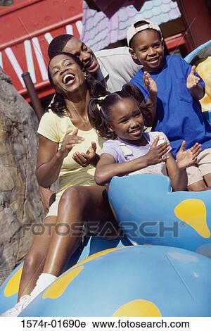 Stock Image - Portrait of parents and their two children in an amusement park. Fotosearch