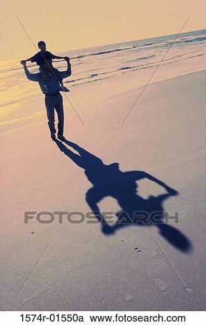 Silhouette of a man carrying his son on his shoulders at the beach View Large Photo Image Stock Image - Silhouette of a man carrying his son on his shoulders at the beach. Fotosearch