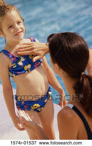 Woman applying sunscreen lotion on her daughter at a poolside View Large Photo Image Stock Photo - Woman applying sunscreen lotion on her daughter at a poolside. Fotosearch