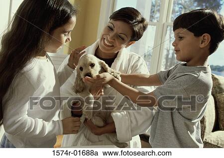Stock Image - Woman holding a puppy out for her son and daughter. Fotosearch