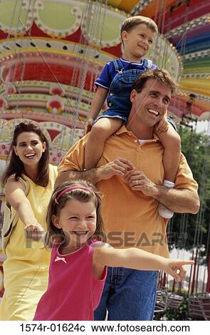 Stock Image - Young couple at an amusement park with their son and daughter. Fotosearch