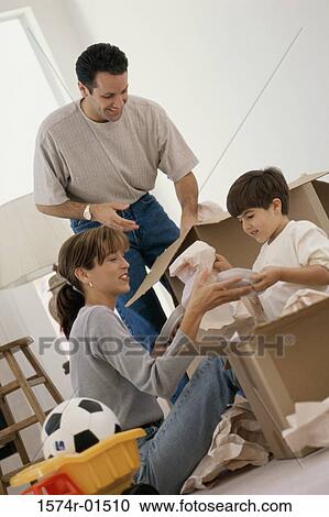 Stock Image - Young couple unpacking boxes with their son. Fotosearch