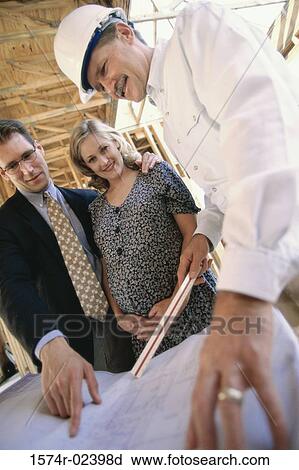 Stock Image - Architect discussing blueprints with a mid adult couple. Fotosearch