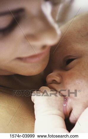 Stock Photo - Close-up of a mother holding her baby boy sucking his thumb. Fotosearch