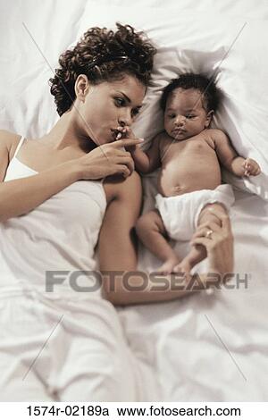 High angle view of a mother lying on a bed with her baby boy View Large Photo Image Stock Image - High angle view of a mother lying on a bed with her baby boy. Fotosearch