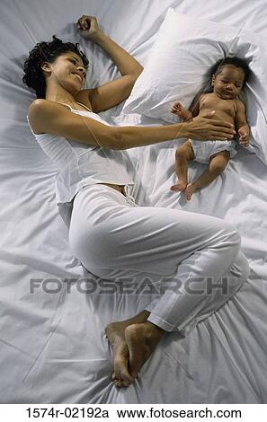 High angle view of a mother lying on a bed with her baby boy View Large Photo Image Stock Image - High angle view of a mother lying on a bed with her baby boy. Fotosearch