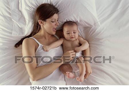 High angle view of a mother lying on a bed with her baby boy View Large Photo Image Stock Image - High angle view of a mother lying on a bed with her baby boy. Fotosearch