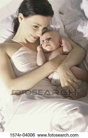 High angle view of a mother lying on a bed with her baby boy View Large Photo Image Stock Photograph - High angle view of a mother lying on a bed with her baby boy. Fotosearch