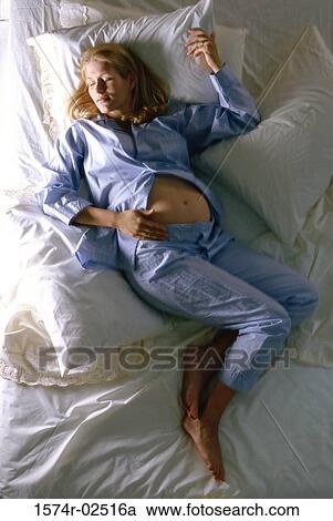 Stock Image - High angle view of a pregnant woman sleeping on a bed. Fotosearch