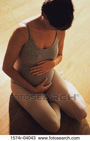 High angle view of a pregnant woman touching her abdomen View Large Photo Image Stock Image - High angle view of a pregnant woman touching her abdomen. Fotosearch