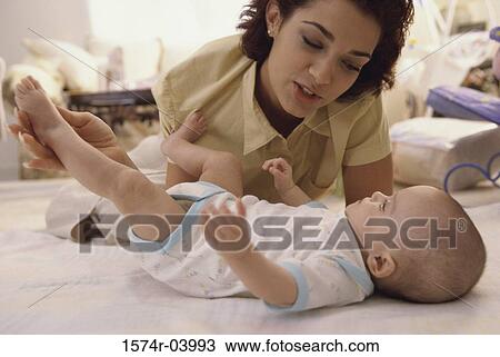 Mother leaning over a baby boy lying down on a bed View Large Photo Image Stock Image - Mother leaning over a baby boy lying down on a bed. Fotosearch