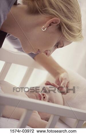 Mother looking at her baby boy in a crib View Large Photo Image Stock Image - Mother looking at her baby boy in a crib. Fotosearch