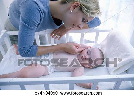 Mother looking at her baby boy in a crib View Large Photo Image Stock Image - Mother looking at her baby boy in a crib. Fotosearch