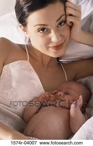 Portrait of a mother lying on a bed with her baby boy View Large Photo Image Stock Photo - Portrait of a mother lying on a bed with her baby boy. Fotosearch