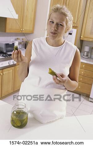 Stock Image - Portrait of a pregnant woman eating pickles. Fotosearch