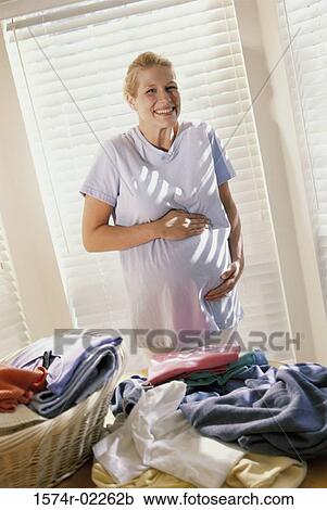 Stock Image - Portrait of a pregnant woman touching her abdomen. Fotosearch