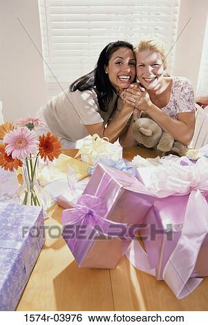 Stock Photograph - Portrait of two young women smiling at a baby shower. Fotosearch