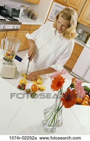 Stock Image - Pregnant woman cutting fruit. Fotosearch
