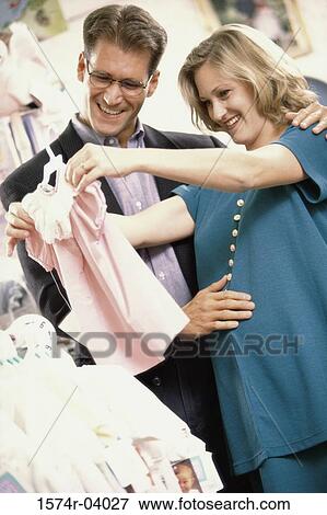 Pregnant woman with her husband shopping for baby clothes View Large Photo Image Stock Photo - Pregnant woman with her husband shopping for baby clothes. Fotosearch