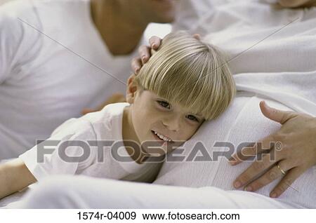 Stock Photo - Son with his head against his pregnant mother's abdomen. Fotosearch
