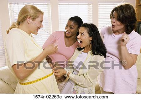Stock Image - Young woman measuring a pregnant woman's abdomen. Fotosearch