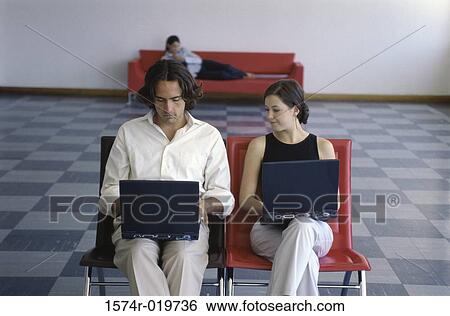Stock Photograph - Businesswoman and a businessman using laptops. Fotosearch
