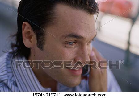 Close-up of a young man talking on a mobile phone View Large Photo Image Stock Image - Close-up of a young man talking on a mobile phone. Fotosearch