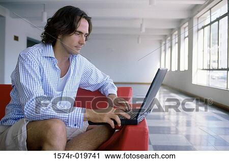 Stock Image - Close-up of a young man using a laptop. Fotosearch