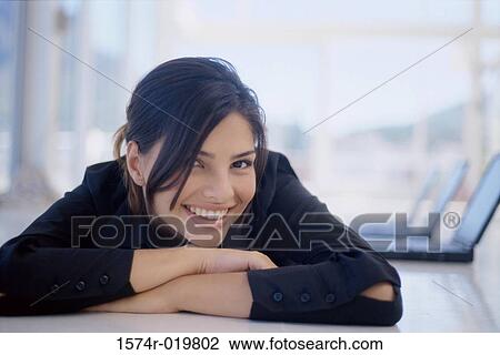 Close-up of a young woman lying on floor with laptops in the background View Large Photo Image Stock Image - Close-up of a young woman lying on floor with laptops in the background. Fotosearch