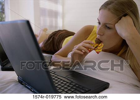 Close-up of a young woman lying on the bed in front of a laptop View Large Photo Image Stock Photography - Close-up of a young woman lying on the bed in front of a laptop. Fotosearch