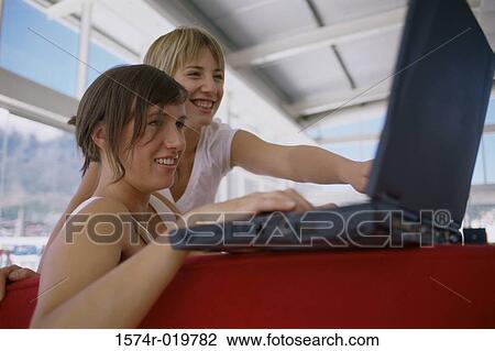 Close-up of two young women looking at a laptop smiling View Large Photo Image Stock Image - Close-up of two young women looking at a laptop smiling. Fotosearch
