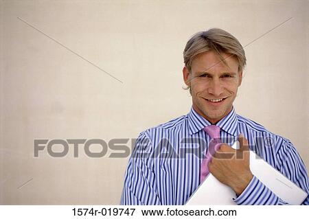 Stock Photo - Portrait of a businessman holding a file smiling. Fotosearch
