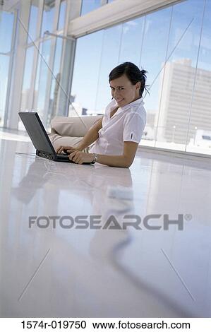 Portrait of a young woman lying on the floor and using a laptop View Large Photo Image Stock Image - Portrait of a young woman lying on the floor and using a laptop. Fotosearch