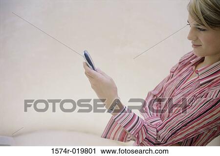 Stock Image - Side profile of a teenage girl operating a mobile pone. Fotosearch