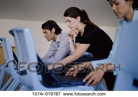 Side profile of two businesswomen and a businessman using laptops View Large Photo Image Stock Photo - Side profile of two businesswomen and a businessman using laptops. Fotosearch