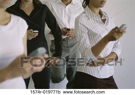 Stock Image - Three young women and a young man operating mobiles phones. Fotosearch