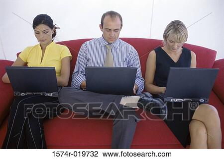 Stock Image - Two businesswomen and a businessman using laptops. Fotosearch