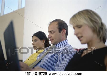 Stock Photo - Two businesswomen and a businessman using laptops. Fotosearch