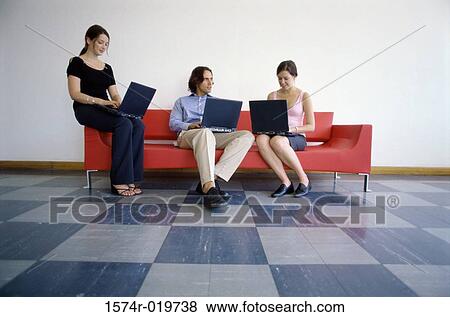 Stock Photo - Two businesswomen and a businessman using laptops. Fotosearch